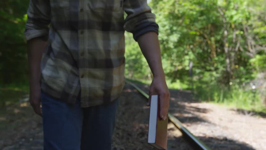 Man With Bible Walking On Train Tracks