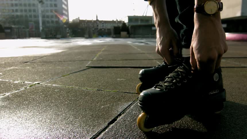 Person leaning forward tying their skates on a cloudy day