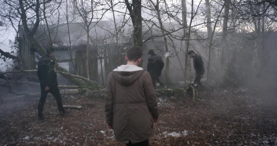 People walking towards house in the forest with smoking coming out of it