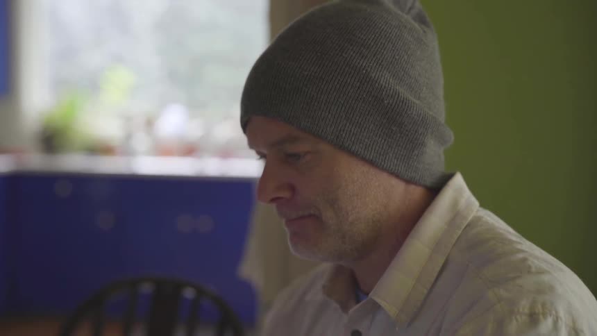Man Working On Computer At Kitchen Table