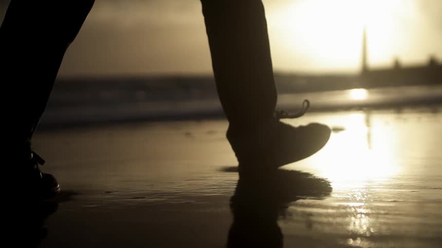 Man walks the beach at sunset