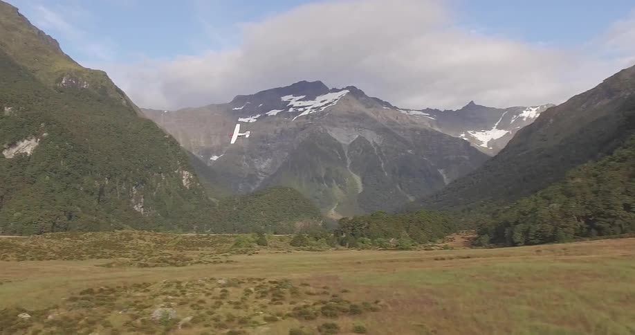 An small airplane circles low in a valley bounded by tall mountains