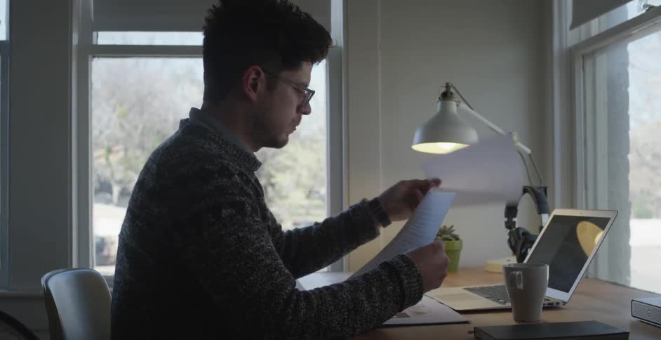 A man looking through papers at a desk