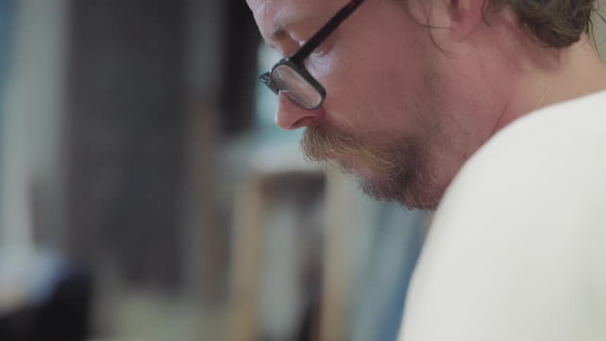 Man in white shirt looking down at work station
