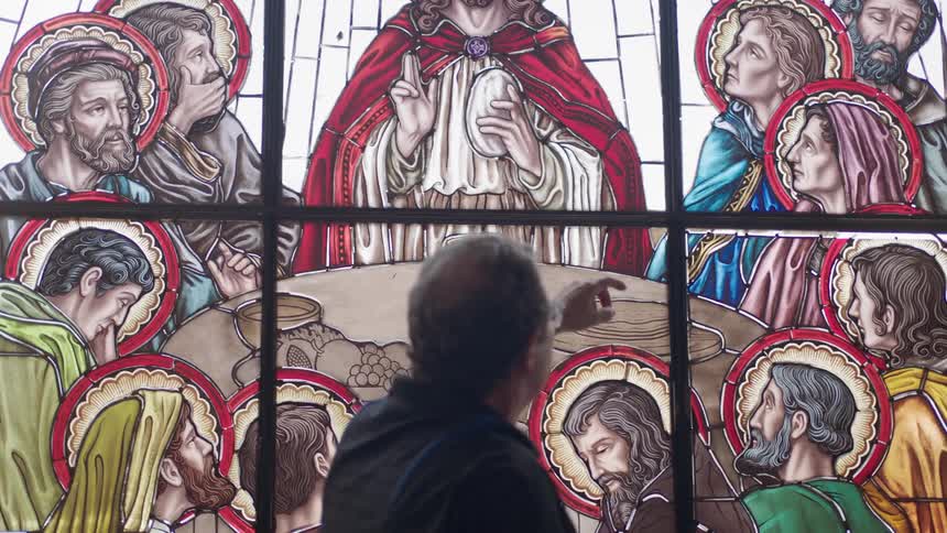 Man walking in front of large stain glass