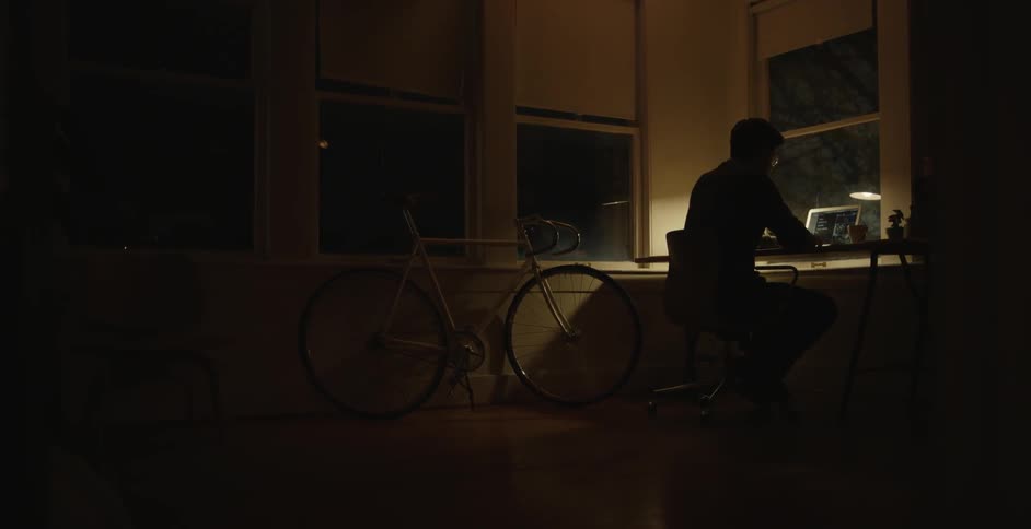 A man sitting in a dark room working on a computer