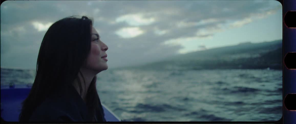 Woman with brown hair sitting on a boat with wind in her hair