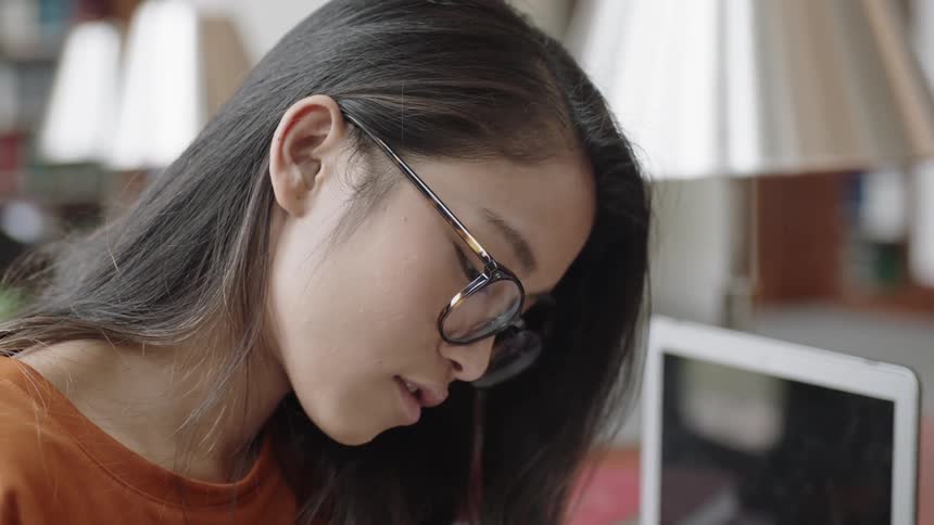 Young student looking down and reading book