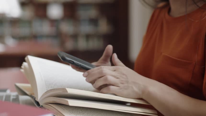 Young adult using phone to take picture of book