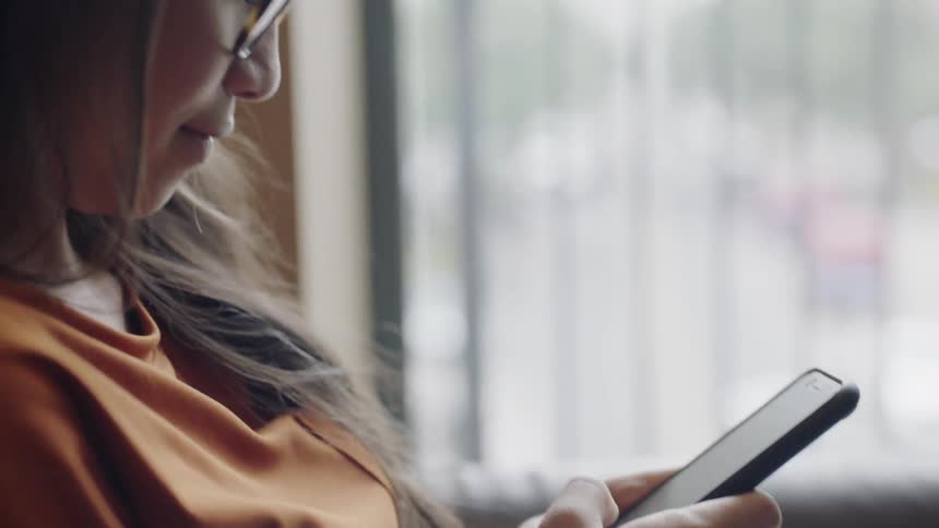Girl using phone by window