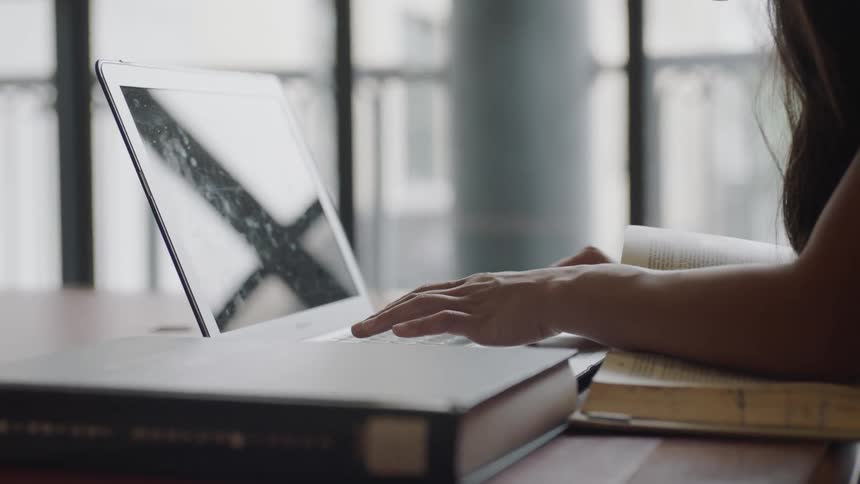 Student leaning over book to work on computer