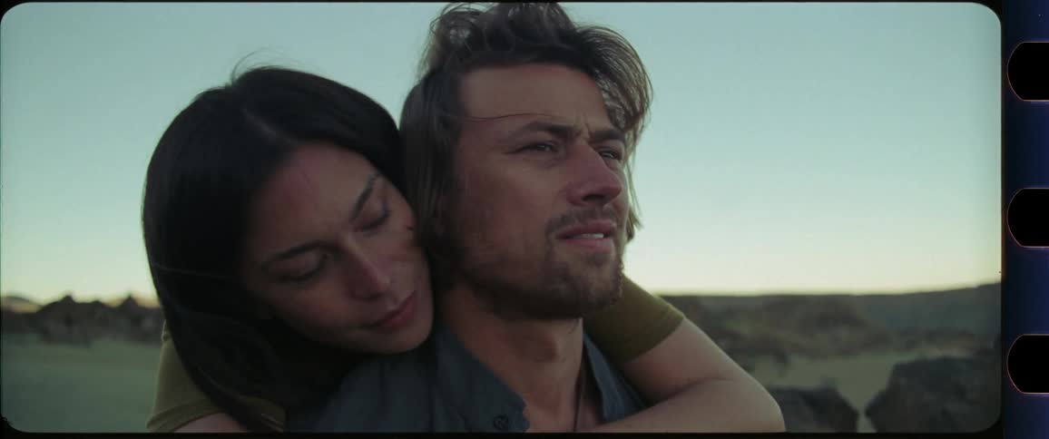 Woman hugging man from behind while looking into the distance