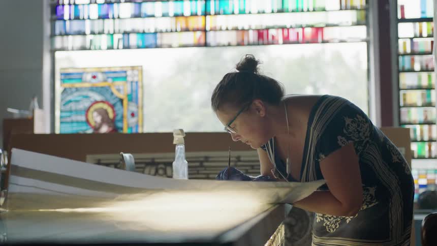 Woman leaning over table in front of colorful window