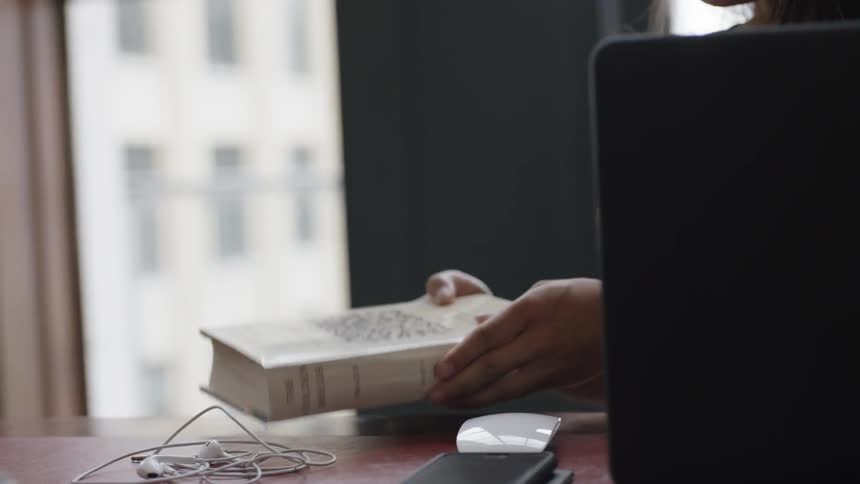 Student moving book over laptop