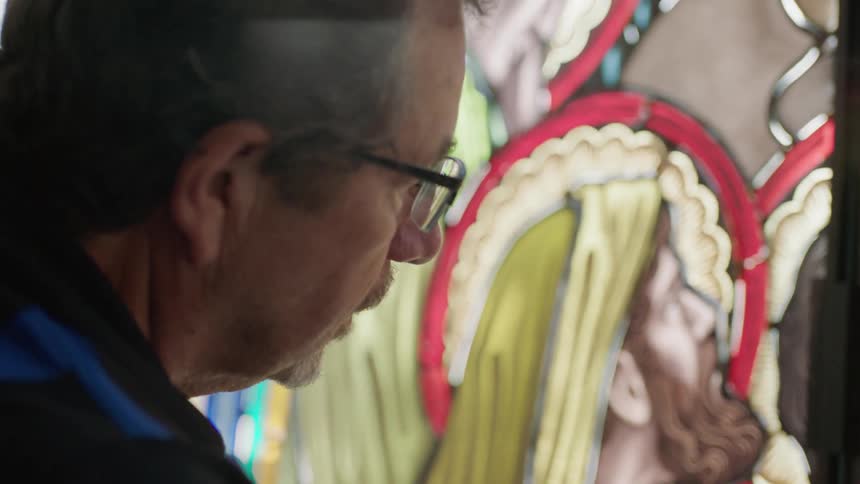 Older man close to stain glass working on project