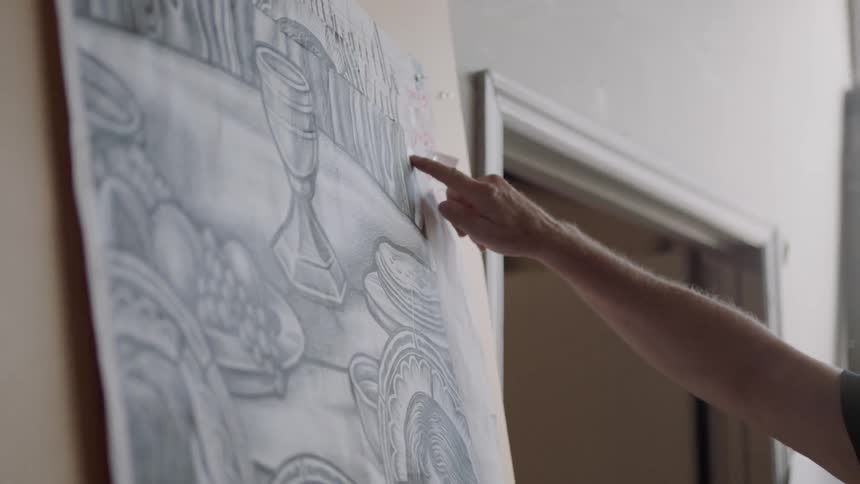 Man points to drawing hanging up