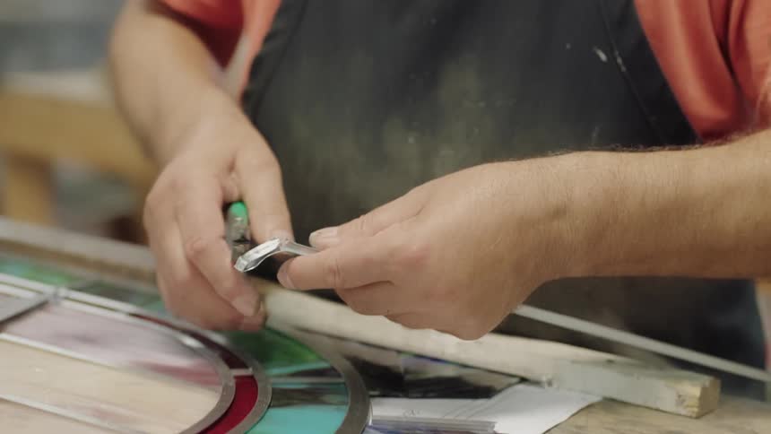 Man wearing glasses cutting metal strip