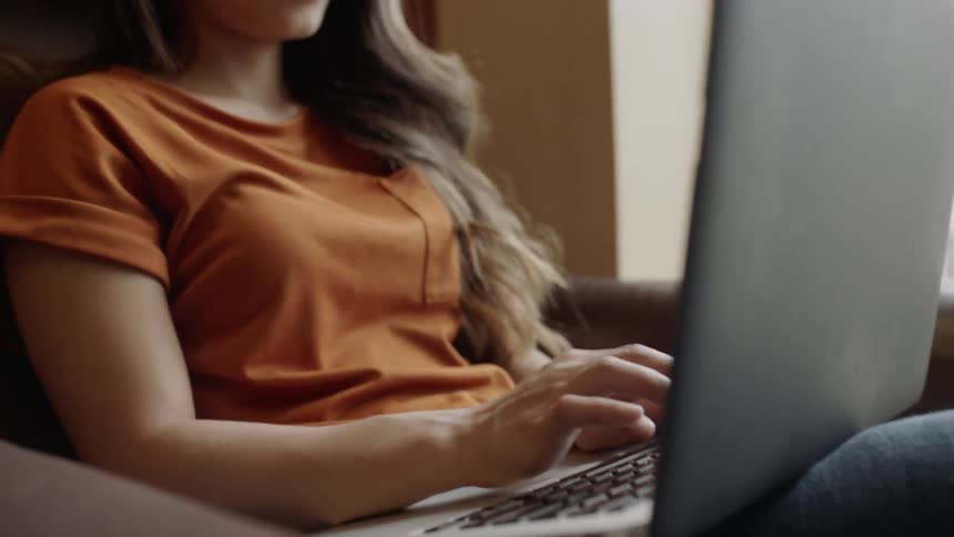 Young adult working on computer and smiles at screen