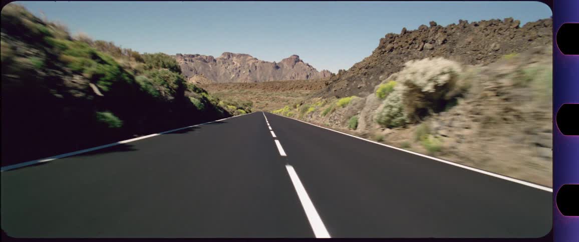 Camera flying above a highway with mountains in the background