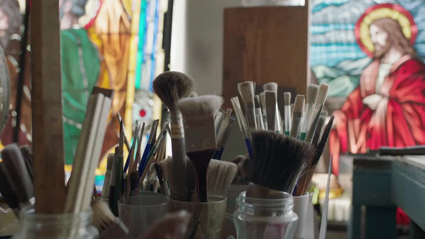 Paint brushes in jars with artwork in the background
