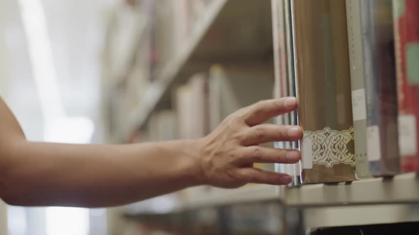 Fingers moving over books in library