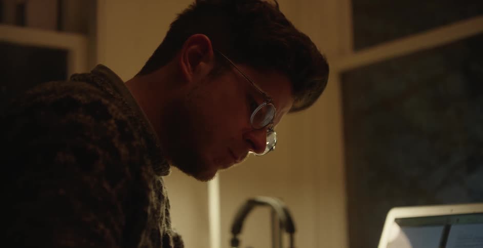 A man looks down at his desk while writing