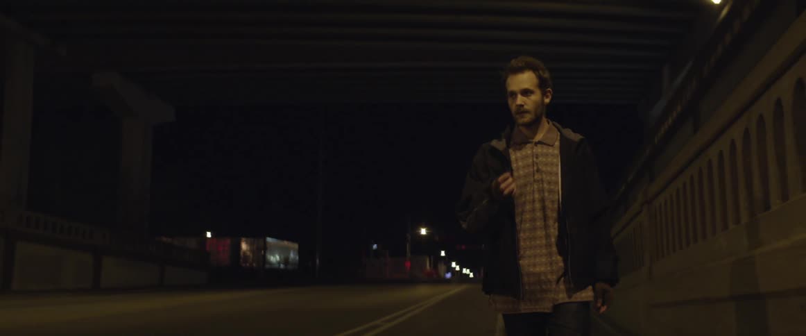 A man smoking a cigarette walks next to a road