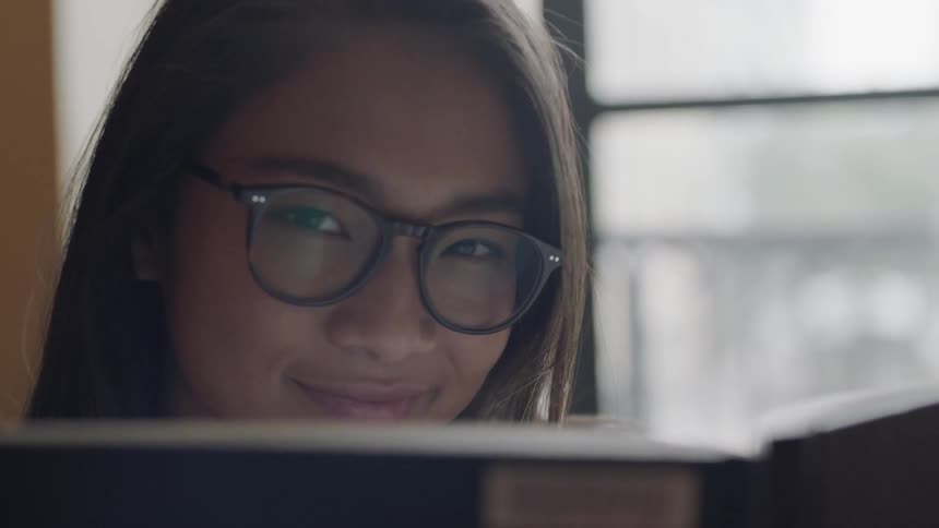 Student wearing glasses looking over book