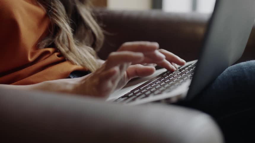 Fingers moving over keyboard on laptop