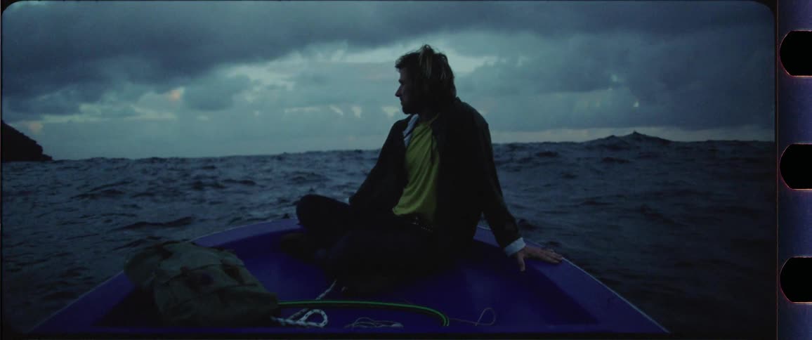 Man sitting at the front of a boat going up and down with the waves