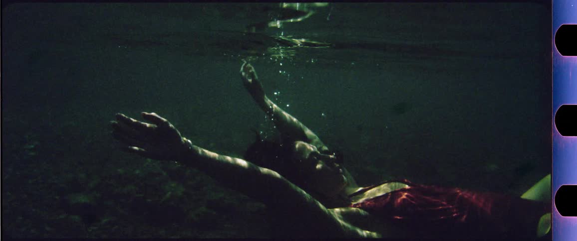 Woman in red bathing suit floating underwater with her eyes closed