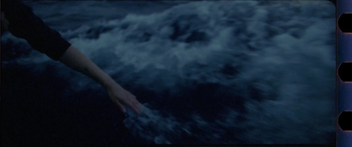 Female hand touching the ocean from a boat while moving