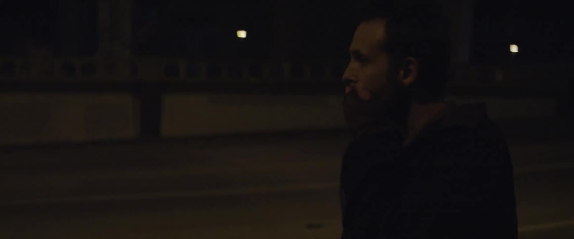 Man walking down a city street at night as a bicyclist rides by
