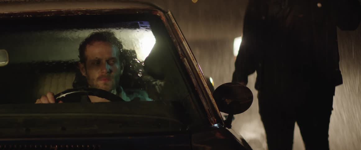 A man in a car being approached during a storm