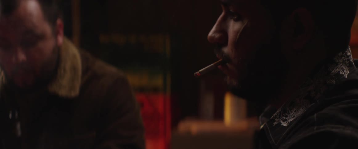 Two men appear to play poker in a seedy club