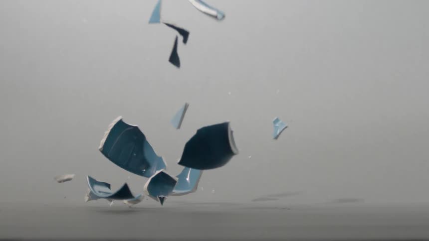 A slow-motion view of a blue ceramic cup crashing to the floor