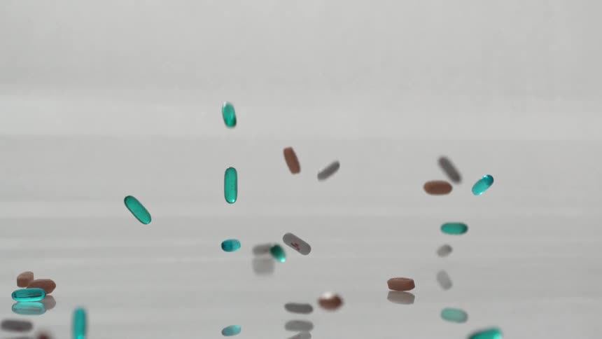 A slow-motion clip of blue and brown capsules falling on the floor