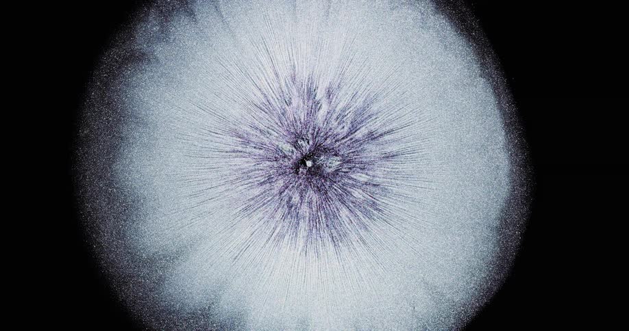 A drop of metallic ink explodes like a star burst