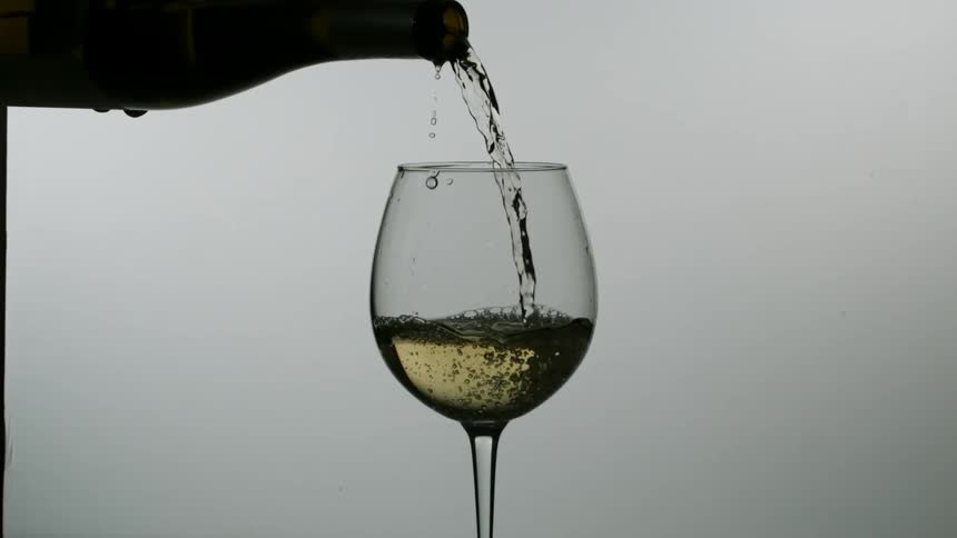 White wine is poured from a bottle into a wine glass