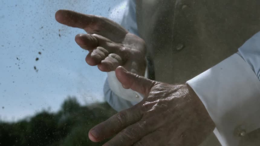 A man rubs his hands together to remove dirt which falls to the ground