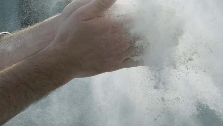 A man claps his chalk filled hands together