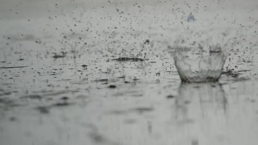 Raindrops falling into a puddle in slow motion