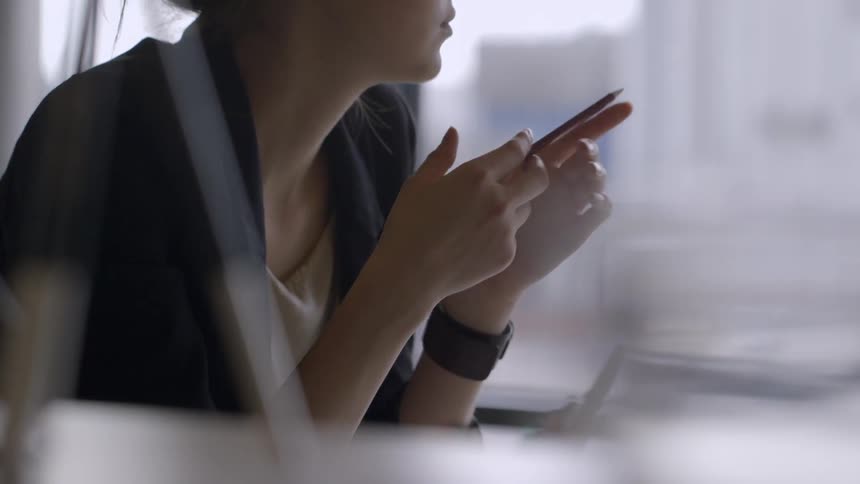 A woman sits at her desk and twirls a pencil in her hands