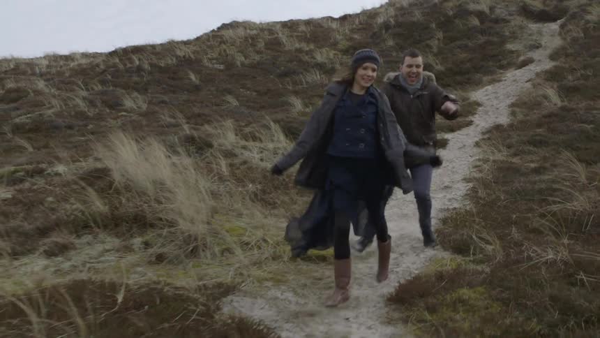 Two people running downhill on a trail on a cloudy day