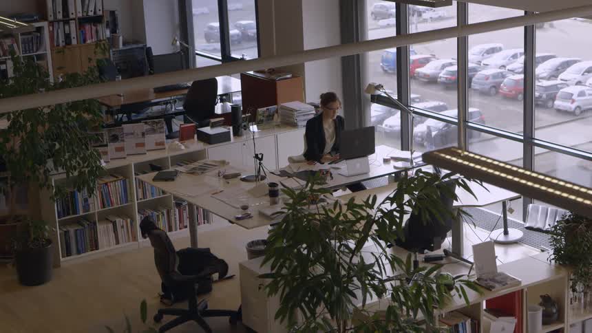 A woman sits in a modern office working at her laptop
