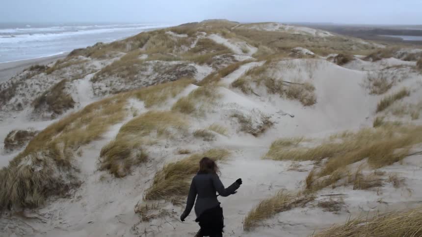 A woman running down a sand dune