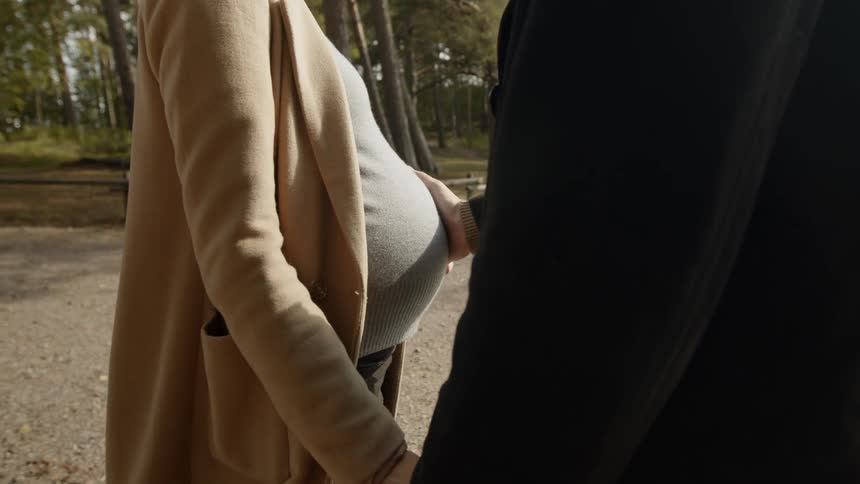 Expecting Couple Walking In The Forest