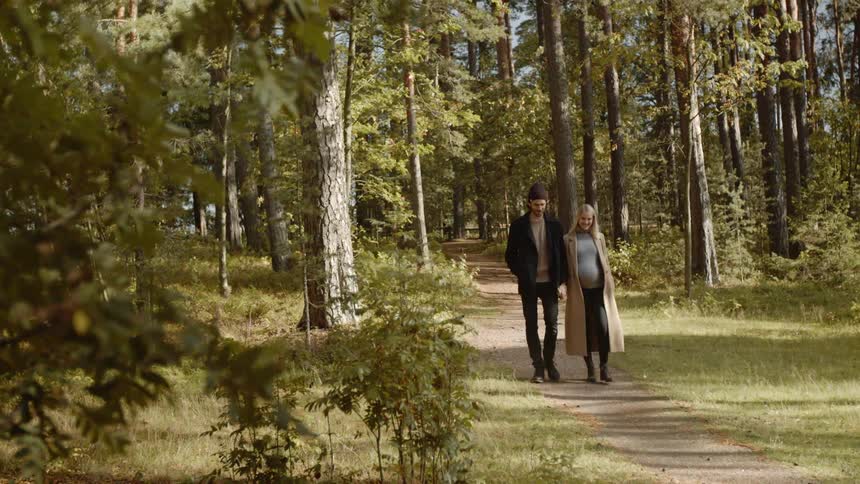 Expecting Couple Walking In The Forest