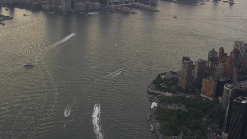 City buildings and skyscrapers on shore and boats leaving wakes in the harbor