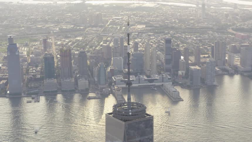 The spire of the freedom tower stands tall above the harbor and city at sunset